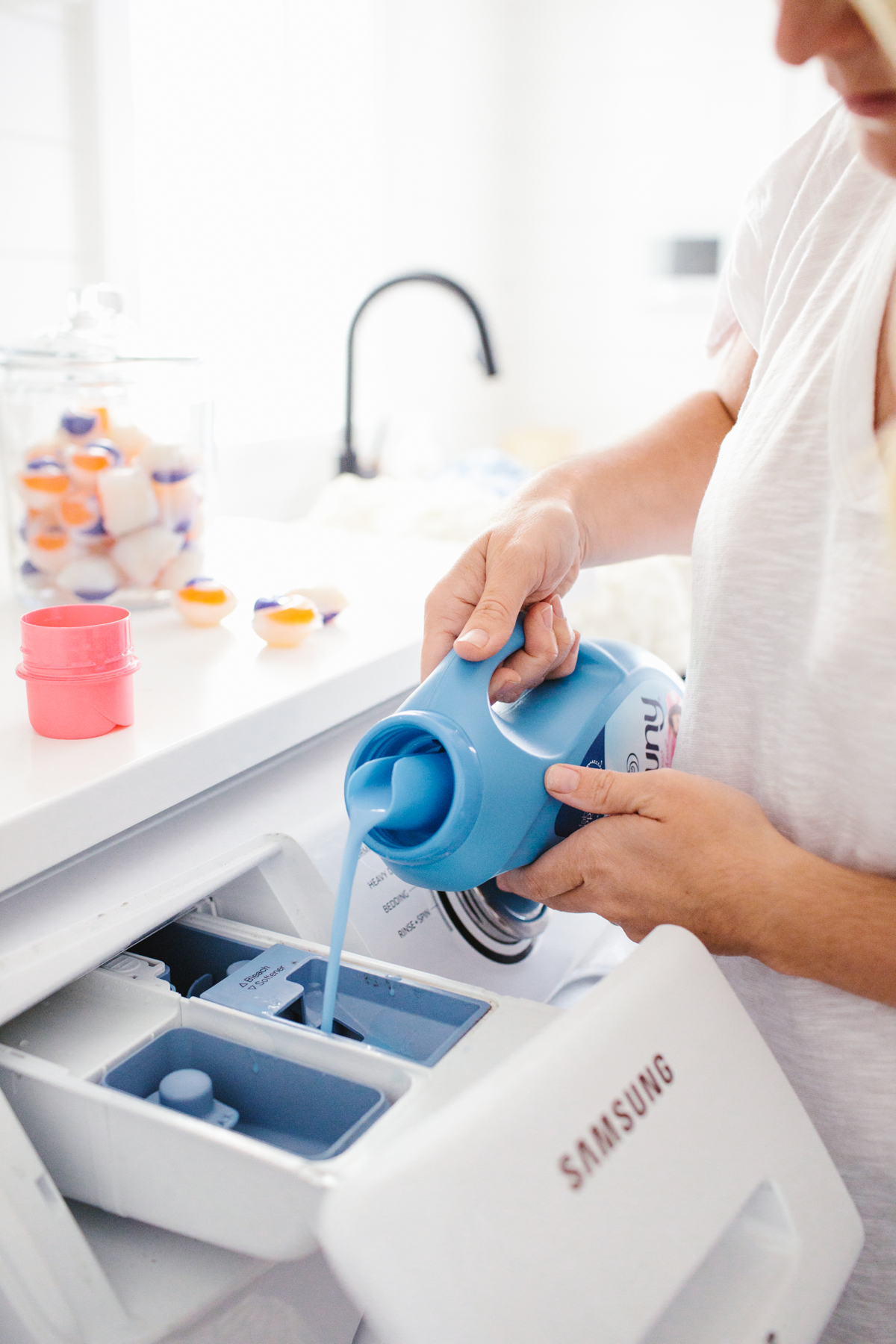 Monika pouring fabric conditioner into washing machine