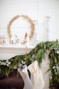 garland on mantel with stockings and glitter homes, candlesticks on the mantel