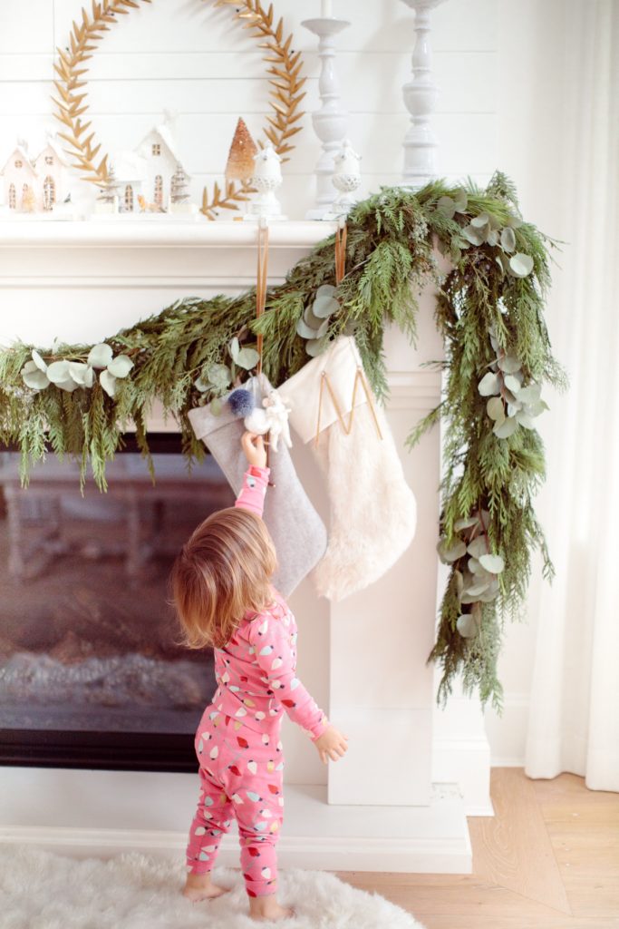 natural garland on fireplace with stocking and toddler