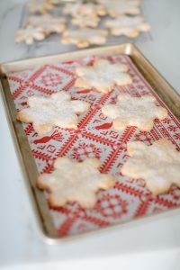 snowflake cookies on sheet pan with festive parchment paper