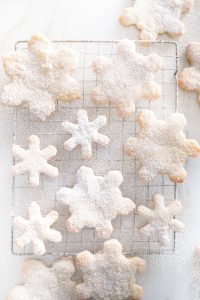 overhead of snowflake cookies dusted with icing sugar on cooling rack