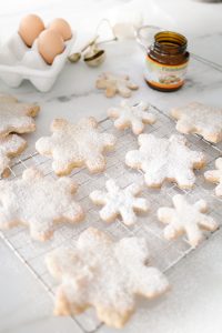 snowflake cookies on cooling rack dusted with icing sugar