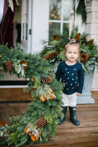 little girl outside but large christmas wreath