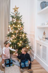 little boy and girl in front of christmas tree