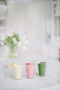 smoothies on counter red, tropical and green flowers in background