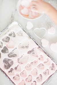 cutting out marshmallows heart shaped and different shades of pink