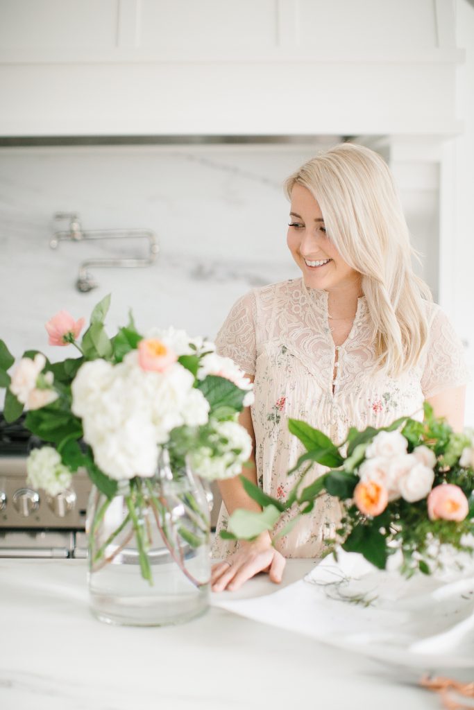 women arranging flowers in white kitchen