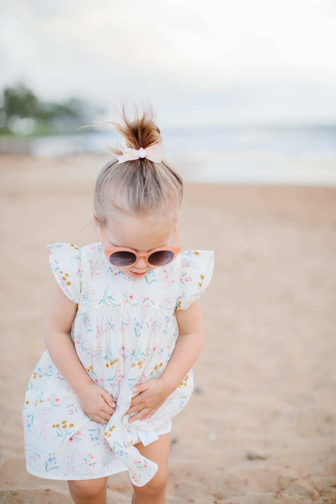 little girl on beach in cute dress hair in a bow