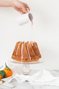 pouring pink citrus glaze on bundt cake