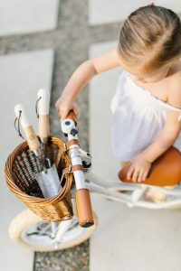 little girl on bike with gardening tools