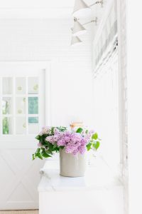 white kitchen and marble with lilacs on counter