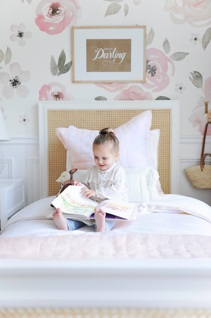 little girl reading book on bed