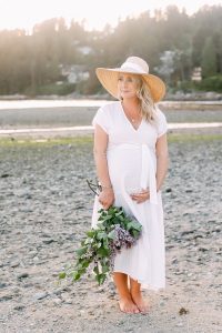 pregnant mom on beach with white dress and lilacs