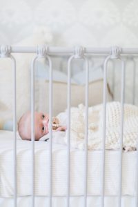 newborn in grey metal crib