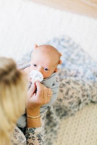 mom putting soother in newborn