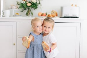 Two little girls hugging with toast in their hands and smiling