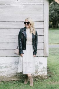 women laughing in sunglasses white dress and leather jacket by barn
