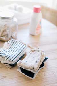 folded baby clothes on wooden table