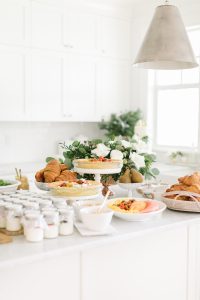 pies, yogurt, croissants, pears, brunch items and floral centrepiece on a white kitchen counter