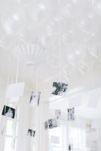 inflated white balloons with black and white photos attached in a white room