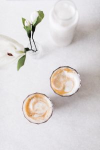 Almond Cashew Mylk Coffee Creamer two glasses of latte with milk and a flower in a jar