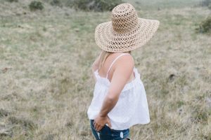 women in straw hat and white tank in field