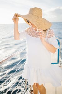 woman wearing overside straw hat with white drop waist dress