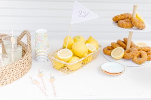 tabletop with 25 cent flag in a basket of lemons and 2 tier plate of donuts