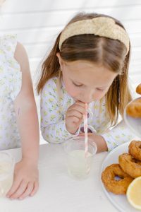 girl drinking lemonade through a pink and white straw