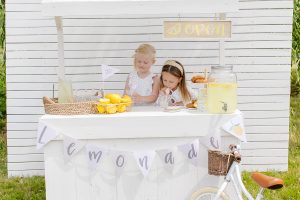 lemonade stand with two young girls drinking lemonade