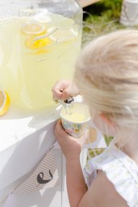 young girl getting a cup of lemonade from a jug