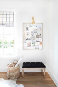 Inspiration board in a corner with a basket and an ottoman seat
