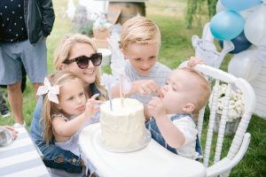 older siblings feeding birthday baby cake
