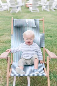 young boy sitting on blue and white lawn chair