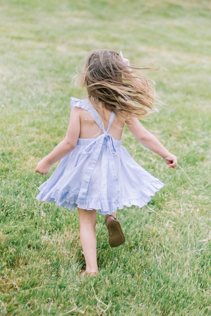 small girl in cute dress running in grass