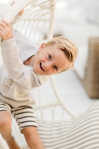 Young boy playfully on a swing wearing sun kissed crew sweater