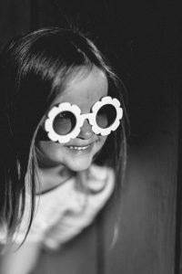 Black and White blonde young smiling girl wearing daisy sunglasses
