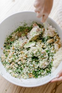 Mixing Loaded Green Chicken Meatballs in Bowl with Wooden Spoon