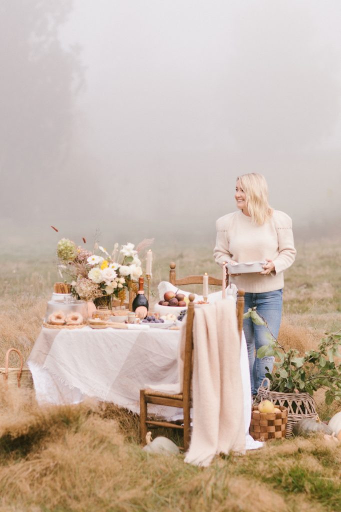 Monika Hibbs in a field next to a table with flowers